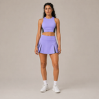 Model wearing the Fitfigura Ace Motion Performance Set – Sculpt Match Form in light purple, featuring a sleeveless crop top and matching pleated skirt, shown from the front.