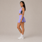 Side-angle studio view of the light purple Fitfigura Ace Motion Performance Set – Sculpt Match Form, showing the fitted crop top and pleated skirt.