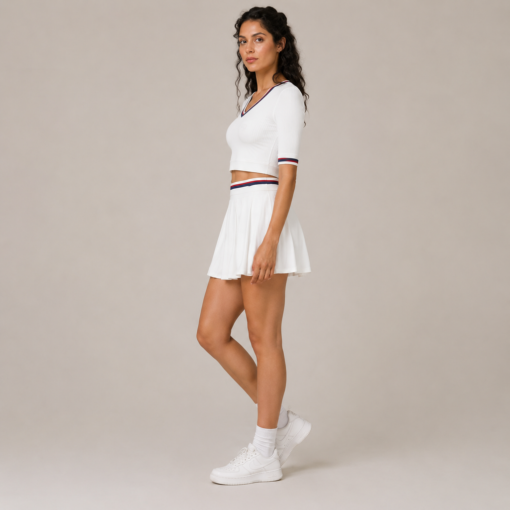 Side-angle studio view of the white Fitfigura Ace Set – Signature Court Form, showing the short-sleeve top, pleated skirt, and sporty court styling.