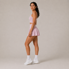 Side-angle studio view of the light pink Fitfigura Ace Skirt – Pleated Form, showing the pleated silhouette and sporty court styling.