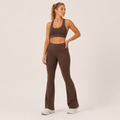Model wearing the Fitfigura Balance Flare Pant – Sculpt Silhouette in brown with a matching brown sports bra, shown from the front.