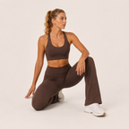 Model seated in the brown Fitfigura Balance Flare Pant – Sculpt Silhouette, showing the soft stretch fit and flared shape.