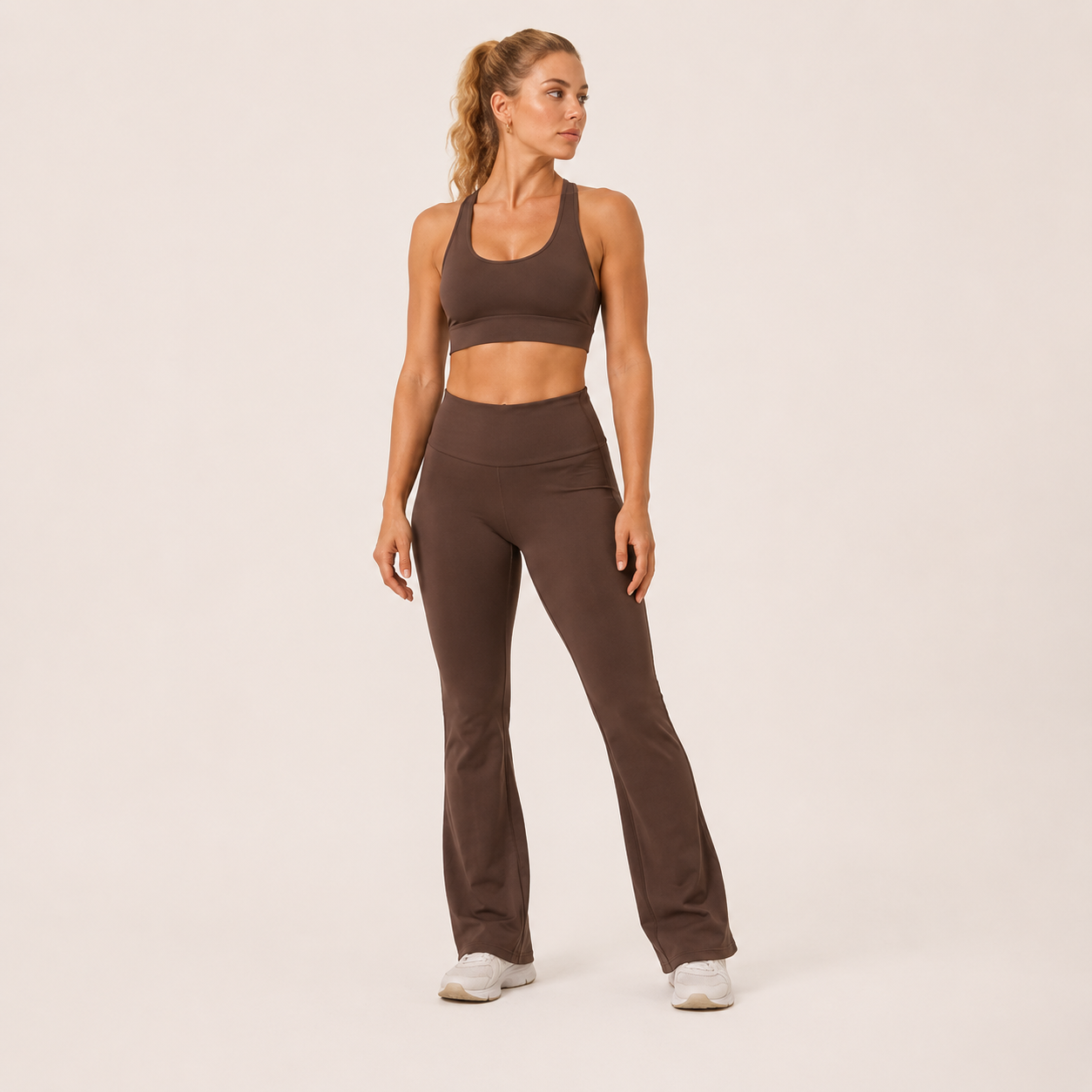 Full-body view of the brown Fitfigura Balance Flare Pant – Sculpt Silhouette, styled with a matching sports bra and white sneakers.