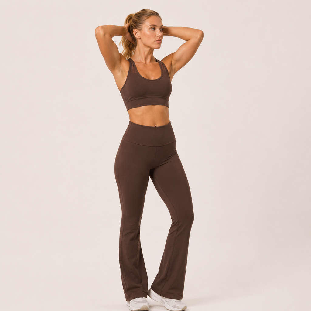 Model posing in the brown Fitfigura Balance Flare Pant – Sculpt Silhouette with arms raised, highlighting the flared leg and fitted waist.