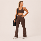 Model wearing the brown Fitfigura Balance Flare Pant – Sculpt Silhouette with a matching top and carrying a black bag.
