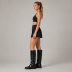 Side view of the Fitfigura Club Skirt – Luxe Resort Form in black, showing the clean side silhouette and fitted mini skirt shape.