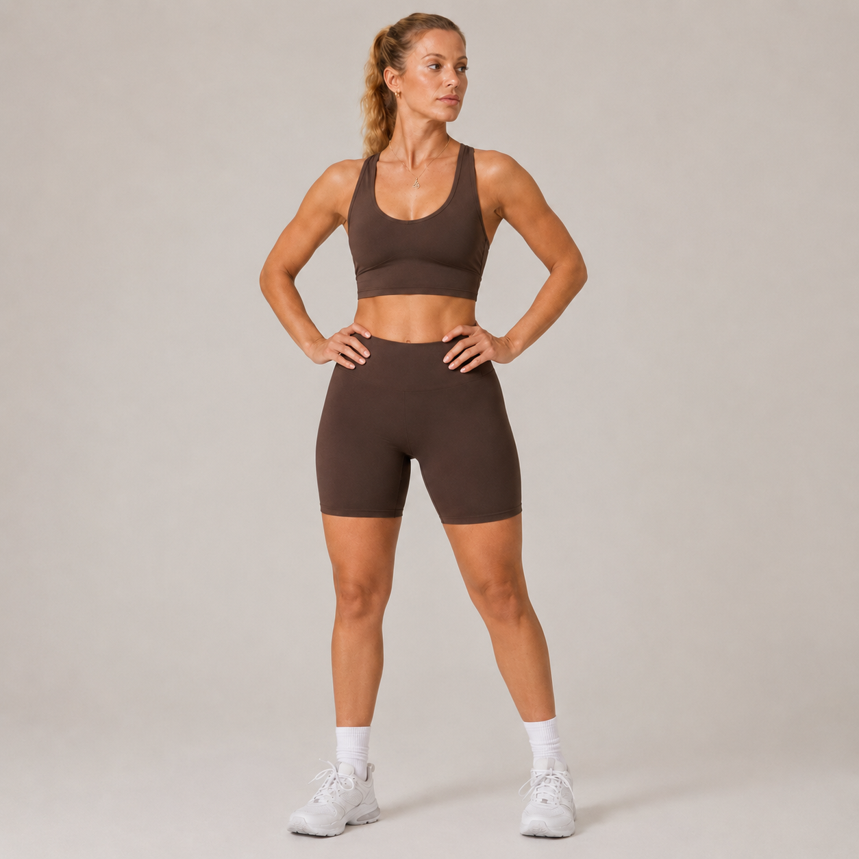 Model wearing the Fitfigura Contour Bra – Defined Sculpt in dark brown with matching shorts, shown from the front with a supportive scoop neckline.