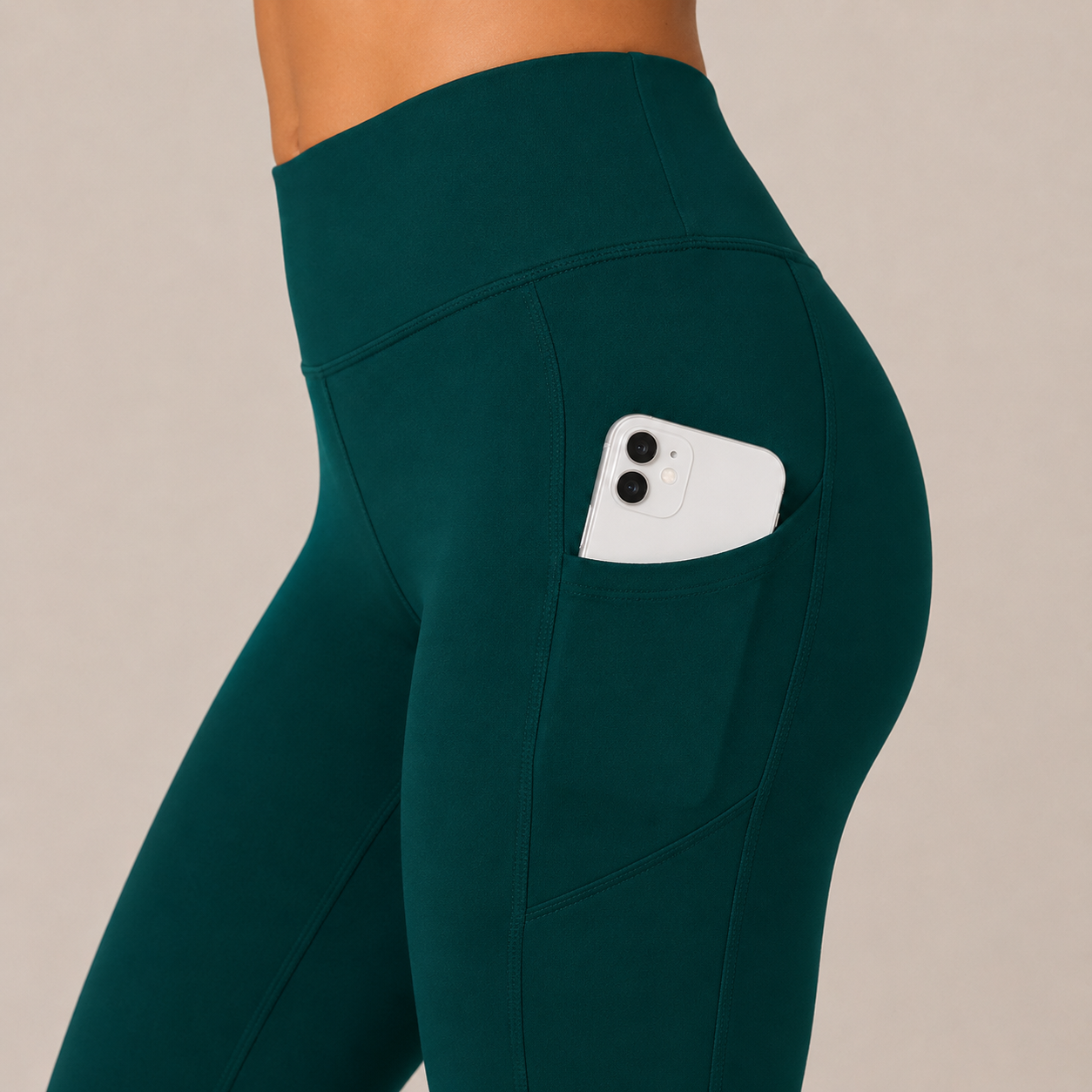 Close-up side view of the deep teal Fitfigura Core Compression Legging showing the utility pocket with a phone.