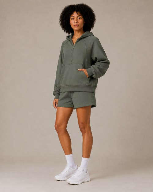 Model posing in the olive green Fitfigura Core Hoodie – Essential Form, highlighting the oversized hoodie and matching short set.