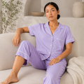 Model wearing the Fitfigura Core Loungewear Set – Essential Form in light purple while seated, showing the relaxed button-up top and matching pants.