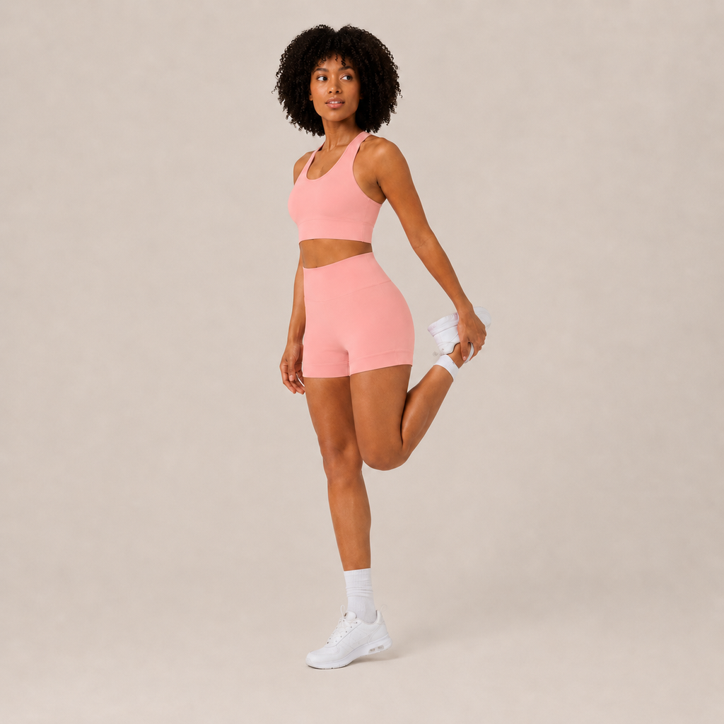 Angled studio view of the coral pink Fitfigura Core Set – Minimal Sculpt Form, highlighting the clean crop top and matching skirt design.