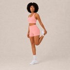 Angled studio view of the coral pink Fitfigura Core Set – Minimal Sculpt Form, highlighting the clean crop top and matching skirt design.