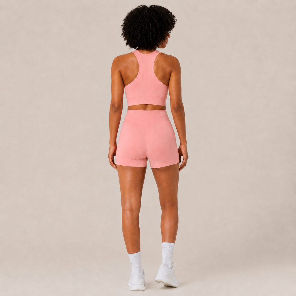 Back view of the Fitfigura Core Set – Minimal Sculpt Form in coral pink, showing the rear fit of the crop top and skirt.