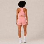 Back view of the Fitfigura Core Set – Minimal Sculpt Form in coral pink, showing the rear fit of the crop top and skirt.