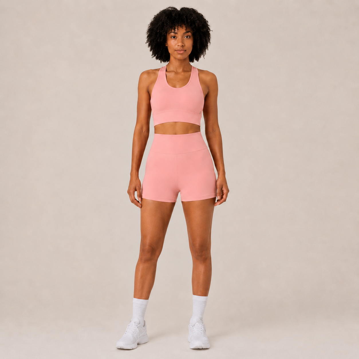 Model wearing the Fitfigura Core Set – Minimal Sculpt Form in coral pink, featuring a sleeveless crop top and matching skirt, shown from the front.