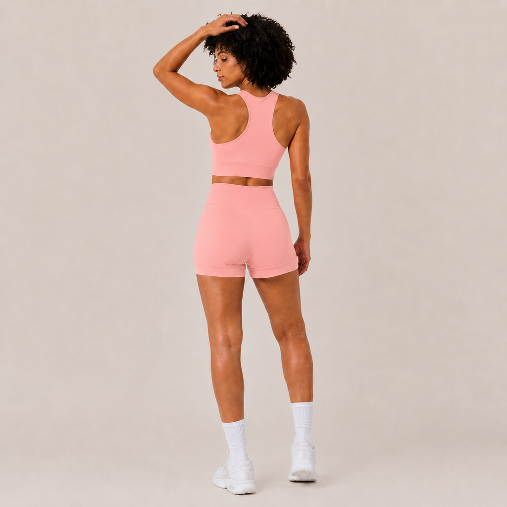 Rear angled view of the coral pink Fitfigura Core Set – Minimal Sculpt Form, highlighting the sculpted fit and sporty silhouette.