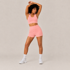 Model wearing the coral pink Fitfigura Core Set – Minimal Sculpt Form with arms raised, highlighting the flexible activewear fit.
