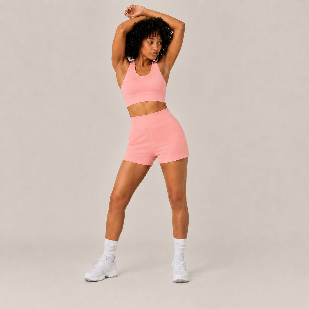 Model wearing the coral pink Fitfigura Core Set – Minimal Sculpt Form with arms raised, highlighting the flexible activewear fit.