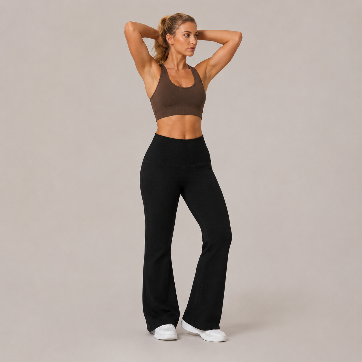 Model wearing the Fitfigura Lounge Flare Pant – Relaxed Luxury Form in black with a brown sports bra, shown from the front with a high-waist fit and flared legs.