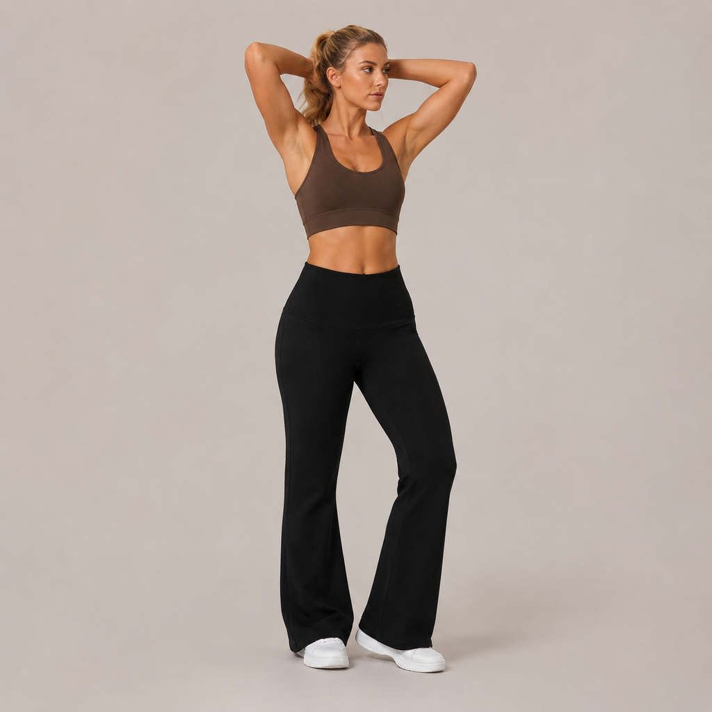 Model wearing the Fitfigura Lounge Flare Pant – Relaxed Luxury Form in black with a brown sports bra, shown from the front with a high-waist fit and flared legs.
