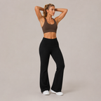 Model wearing the Fitfigura Lounge Flare Pant – Relaxed Luxury Form in black with a brown sports bra, shown from the front with a high-waist fit and flared legs.
