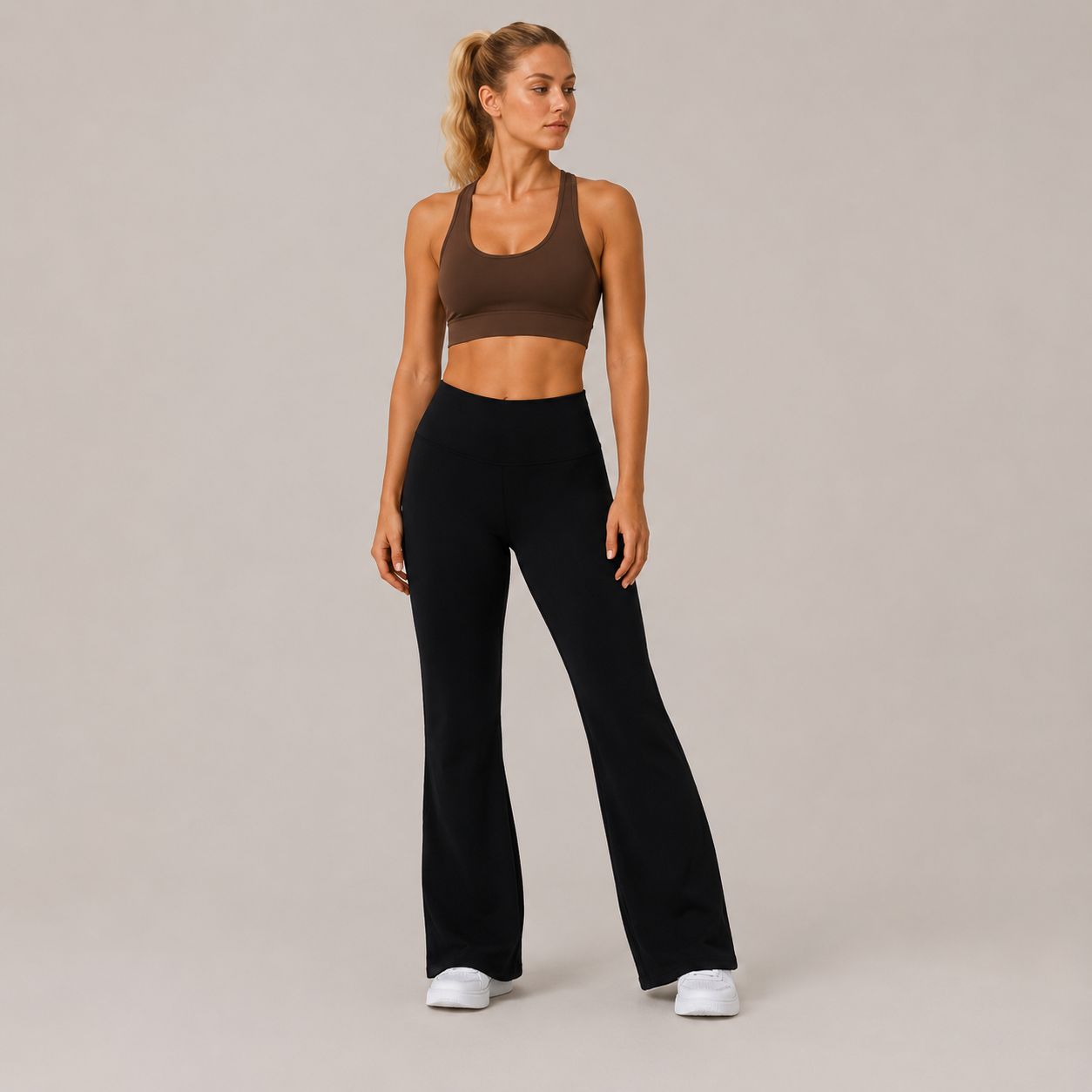 Full-body studio view of the black Fitfigura Lounge Flare Pant – Relaxed Luxury Form, styled with a brown activewear top and white sneakers.