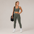 Model wearing the Fitfigura Motion Bra – Sculpt Form in olive green with matching leggings and a black gym bag, shown from the front.