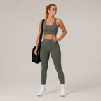 Model wearing the Fitfigura Motion Bra – Sculpt Form in olive green with matching leggings and a black gym bag, shown from the front.