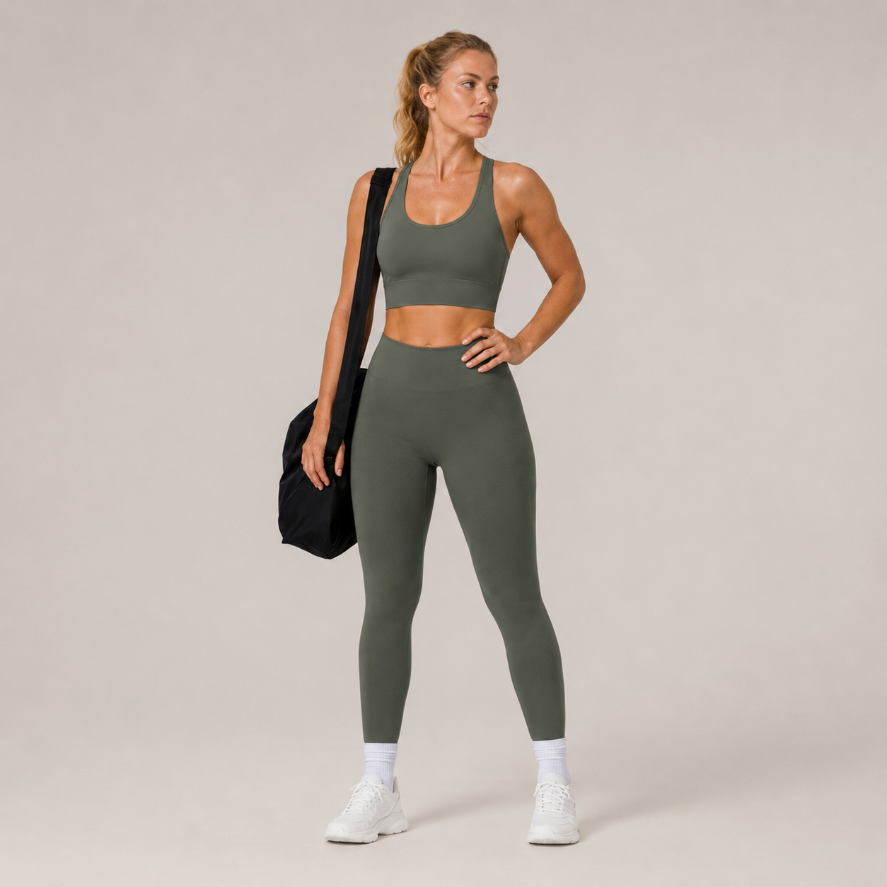 Model wearing the Fitfigura Motion Bra – Sculpt Form in olive green with matching leggings and a black gym bag, shown from the front.