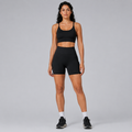 Model wearing the Fitfigura Pocket Short – Utility Performance Form in black with a matching black sports bra and black sneakers, shown from the front.