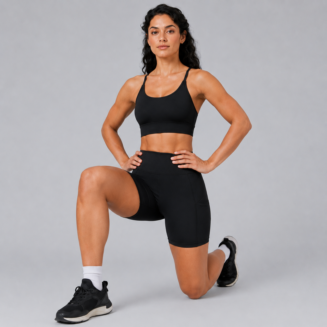 Model kneeling in the Fitfigura Pocket Short – Utility Performance Form in black, highlighting the supportive fit and performance-ready silhouette.