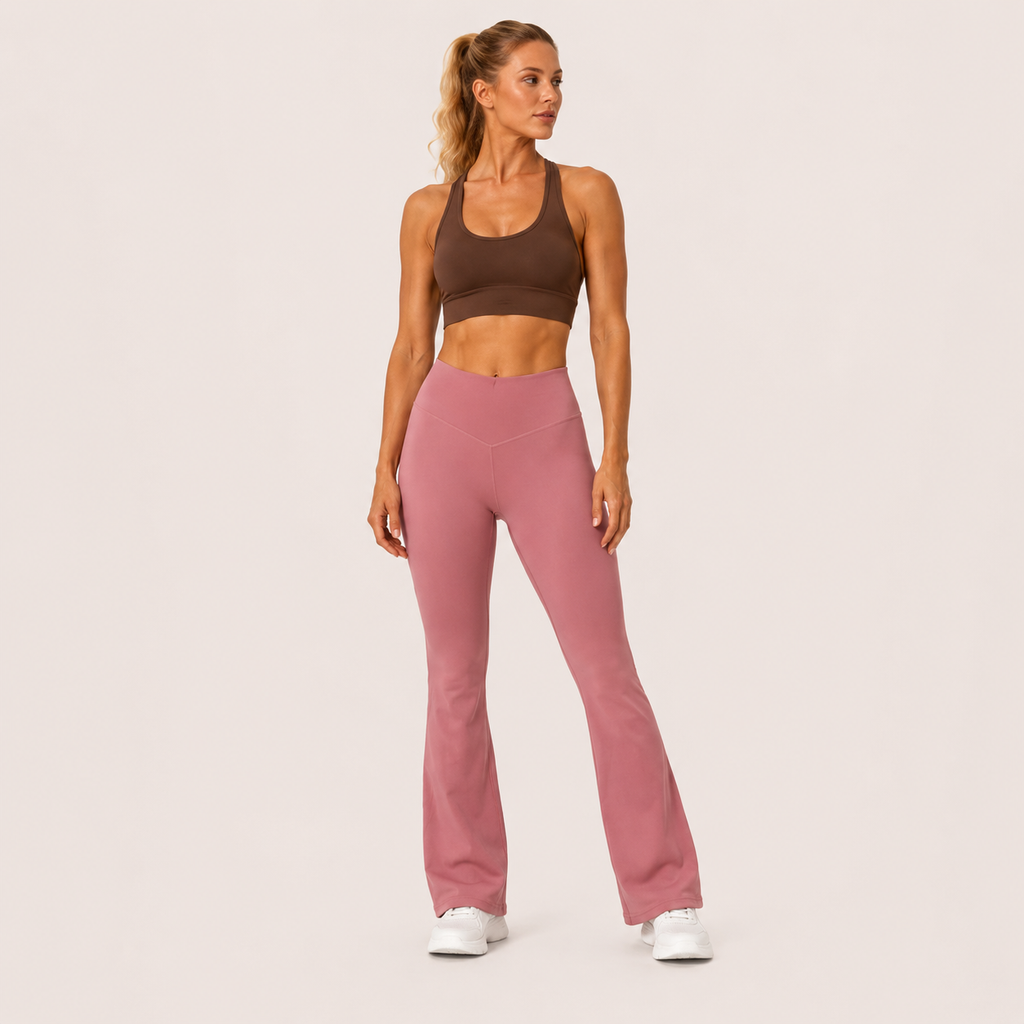 Full-body studio view of the dusty pink Fitfigura Rib Knit Flare Pant – Textured Luxe Form, styled with a brown activewear top and white sneakers.