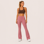 Full-body studio view of the dusty pink Fitfigura Rib Knit Flare Pant – Textured Luxe Form, styled with a brown activewear top and white sneakers.