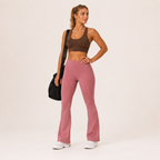 Full-body view of the dusty pink Fitfigura Rib Knit Flare Pant – Textured Luxe Form, showing the smooth fit through the hips and flared hemline.