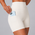 Close-up of the white Fitfigura Rib Short – Soft Sculpt Form showing the side pocket with a phone.