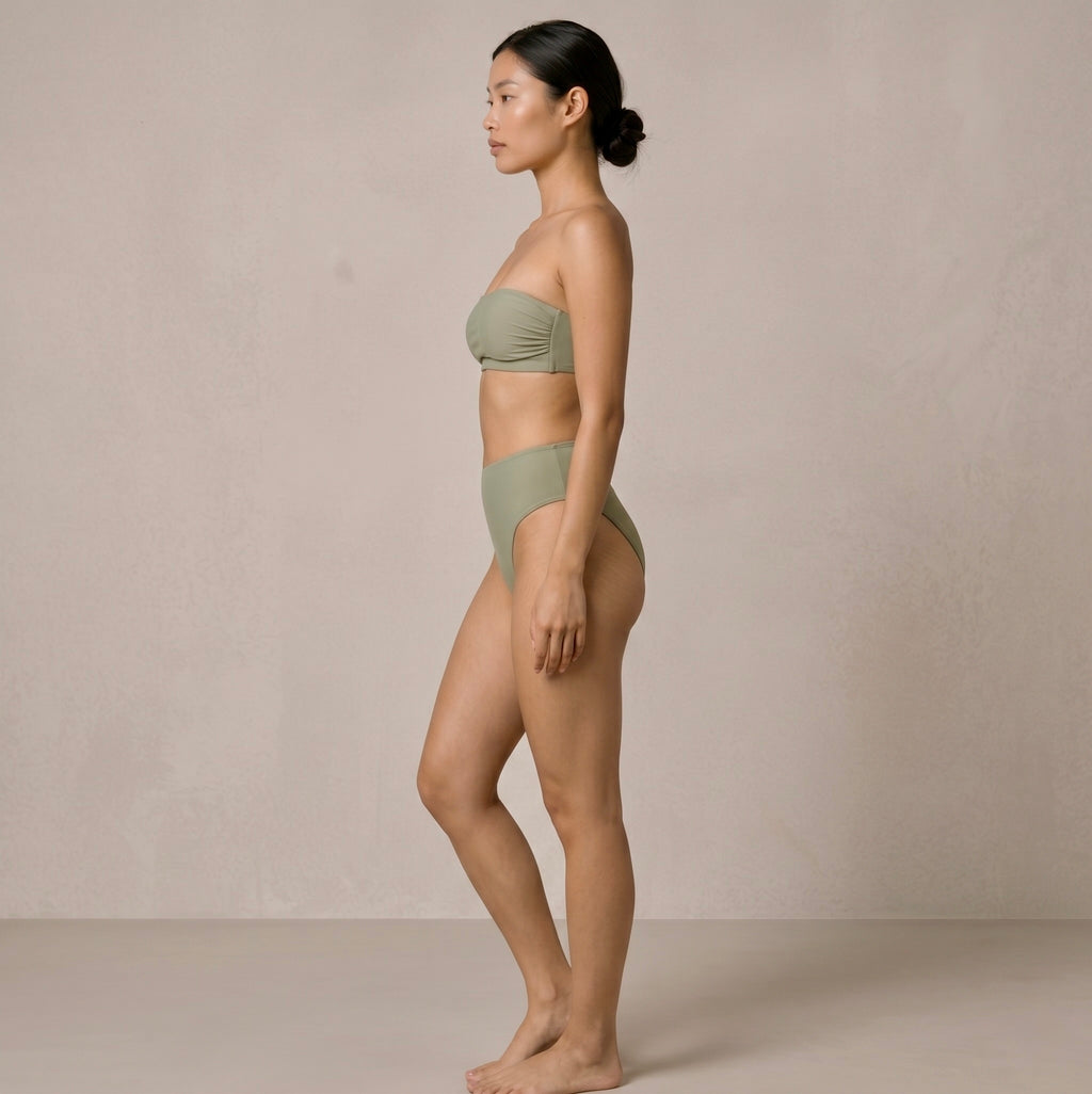 Side profile of the model wearing the sage green Fitfigura Sculpt Bikini – Contour Form, highlighting the clean side shape and high-cut leg line.