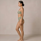 Side profile of the model wearing the sage green Fitfigura Sculpt Bikini – Contour Form, highlighting the clean side shape and high-cut leg line.