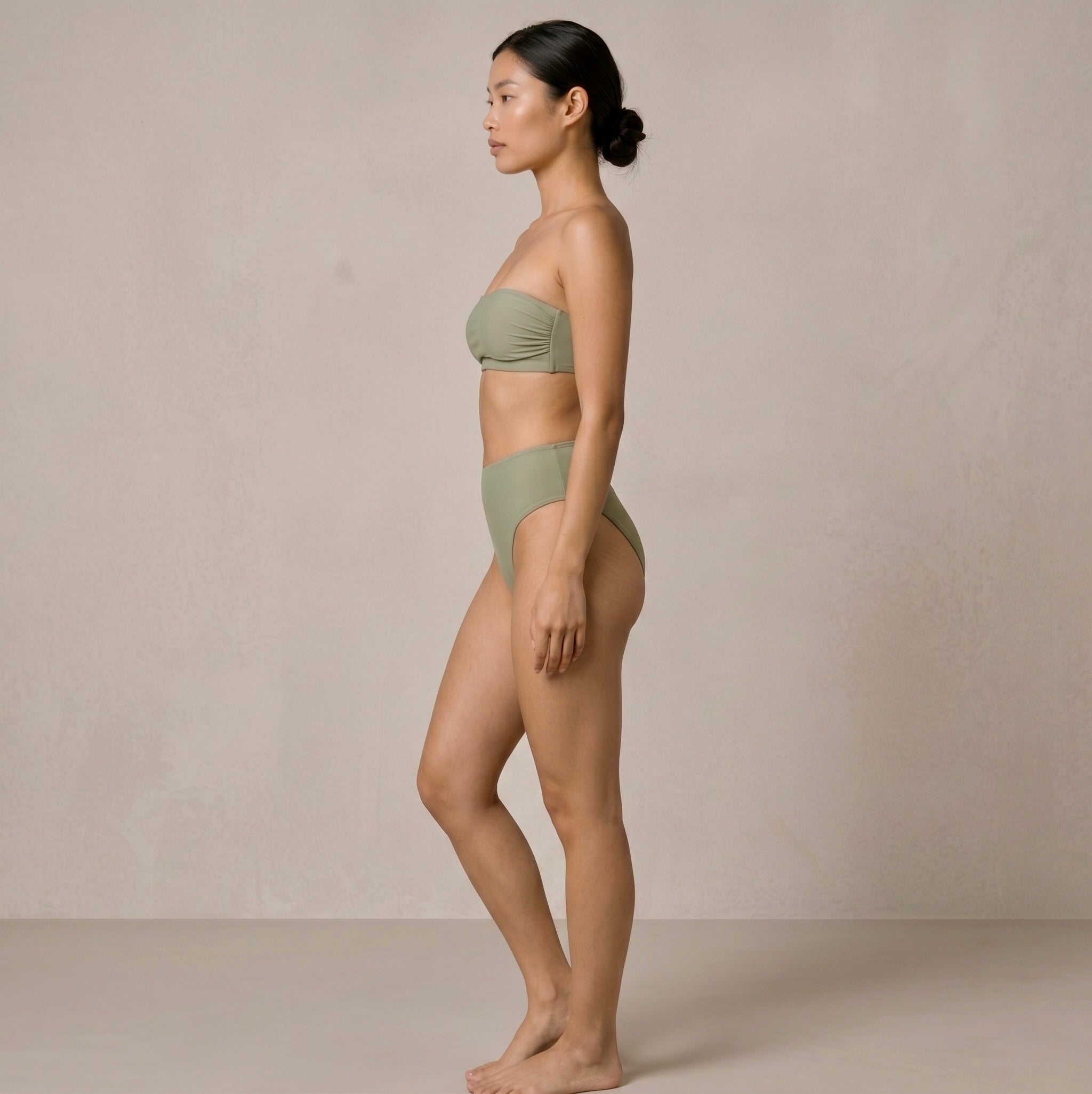Side profile of the model wearing the sage green Fitfigura Sculpt Bikini – Contour Form, highlighting the clean side shape and high-cut leg line.