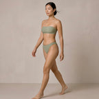 Full-body view of the model walking in the sage green Fitfigura Sculpt Bikini – Contour Form, showing the sleek two-piece swimwear silhouette.