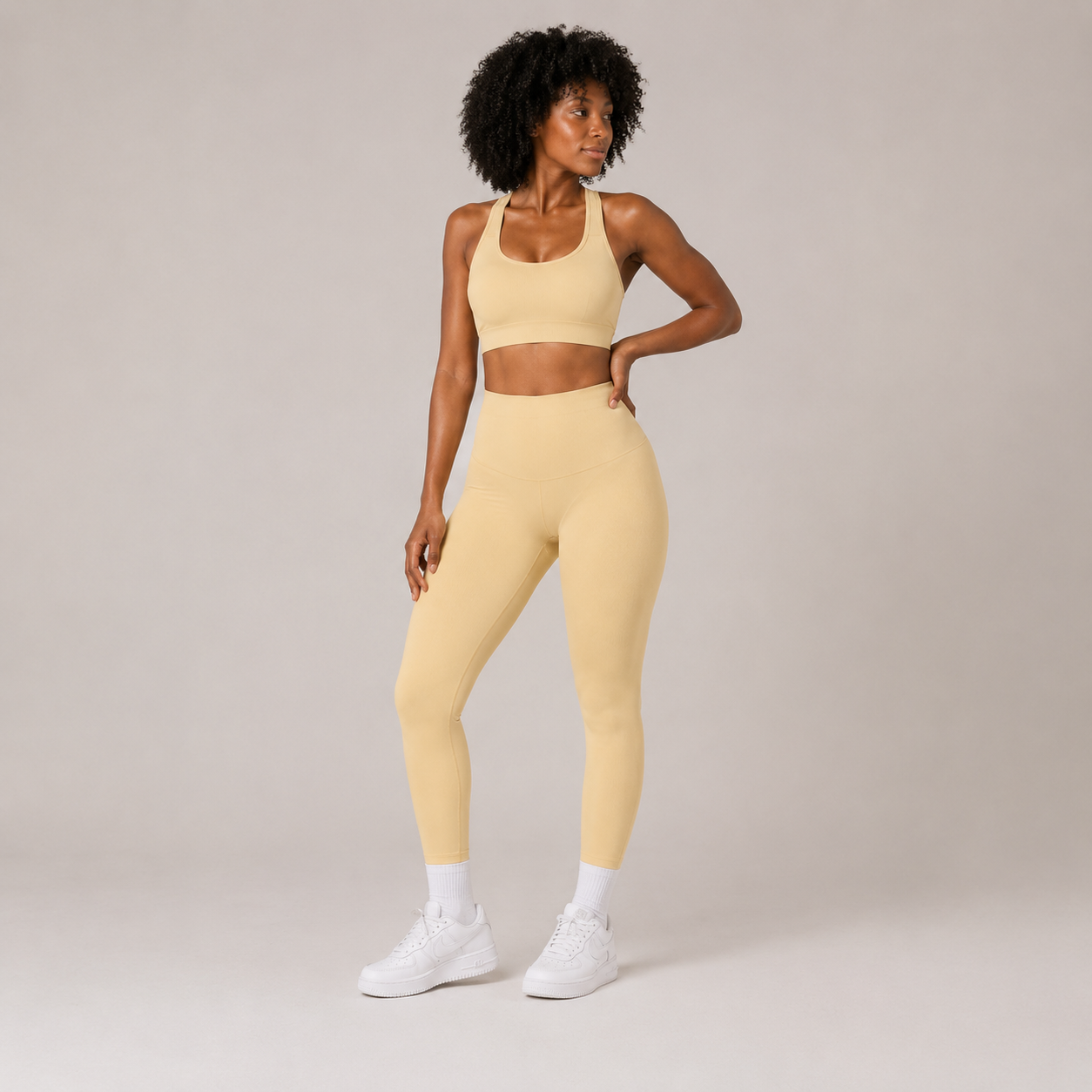 Model posing in the butter yellow Fitfigura Sculpt Set – Seamless Form, showing the coordinated sports bra and leggings silhouette.