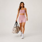 Model wearing the light pink Fitfigura Sculpt Short 6” – Performance Sculpt Form with a matching sports bra and sporty bag.