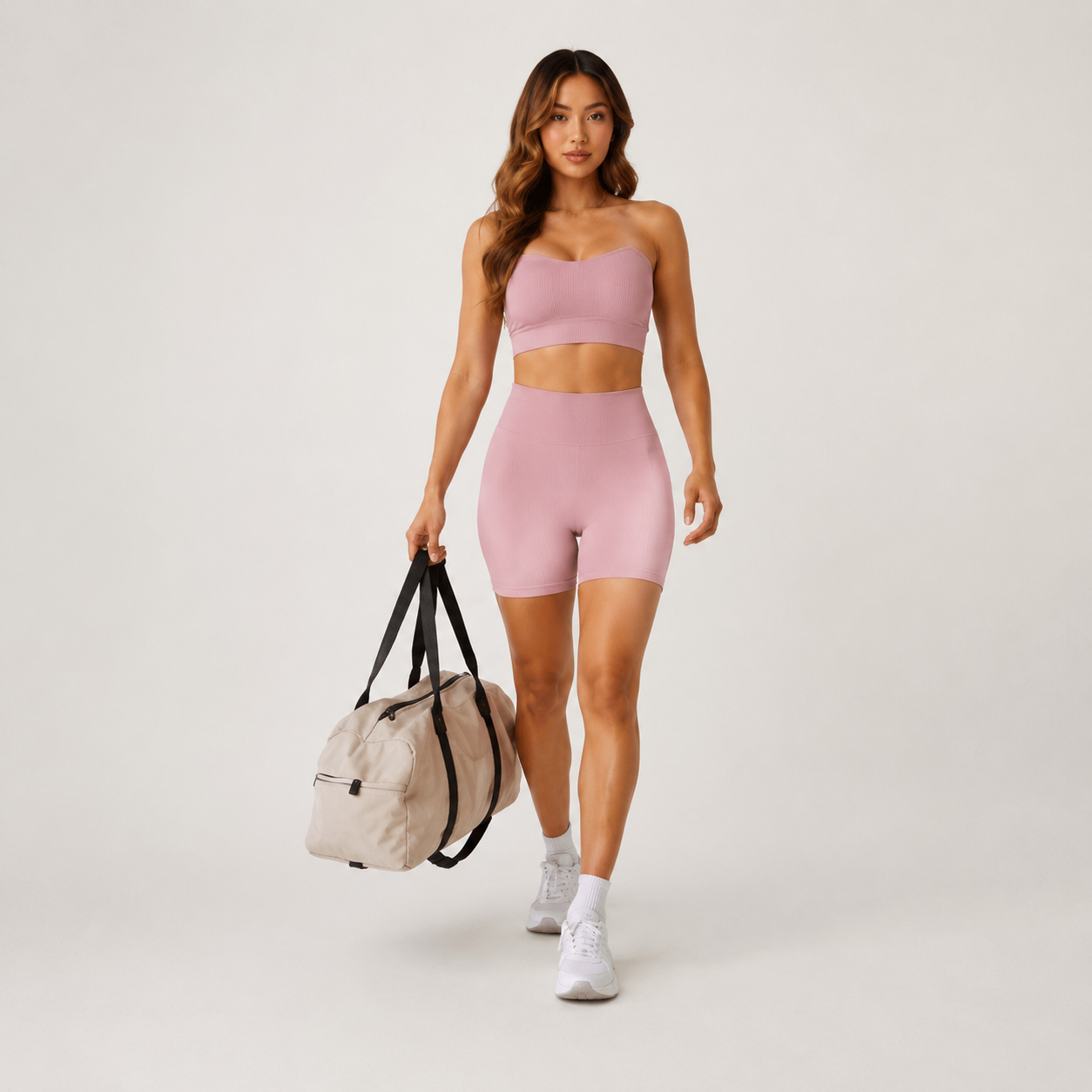 Model wearing the light pink Fitfigura Sculpt Short 6” – Performance Sculpt Form with a matching sports bra and sporty bag.