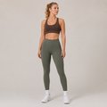 Model wearing the Fitfigura Seamless Legging in olive green with a brown sports bra and white socks, shown from the front.
