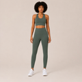 Model wearing the Fitfigura Seamless Set – Performance Sculpt Form in sage green, featuring a sleeveless crop top and matching high-waisted leggings, shown from the front.