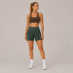 Full-body studio view of the dark green Fitfigura Seamless Short – Athletic Form, styled with a brown activewear top and white sneakers.