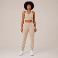 Model wearing the Fitfigura Soft Ribbed Set – Luxe Comfort Form in cream, featuring a sleeveless crop top and relaxed jogger pants, shown from the front.