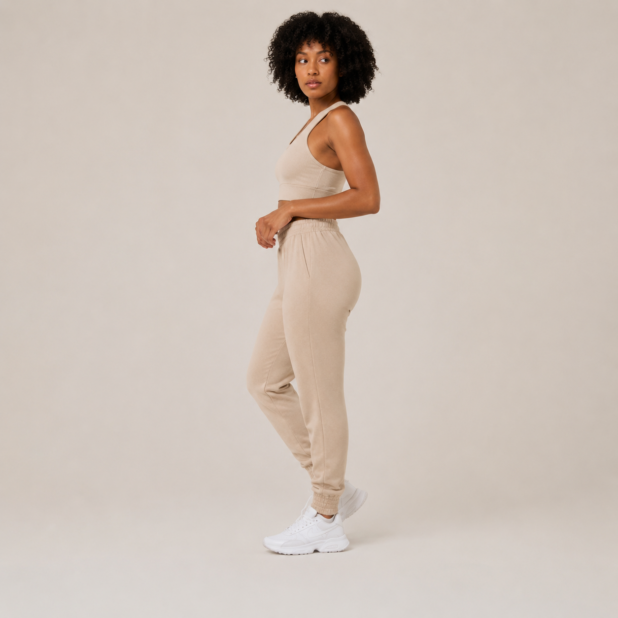 Side view of the Fitfigura Soft Ribbed Set – Luxe Comfort Form in cream, showing the cropped top and tapered jogger silhouette.