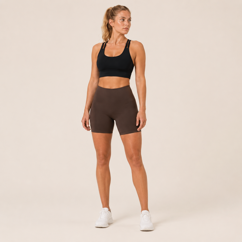 Full-body studio view of the black Fitfigura Studio Bra – Soft Flow, styled with fitted shorts and white sneakers.
