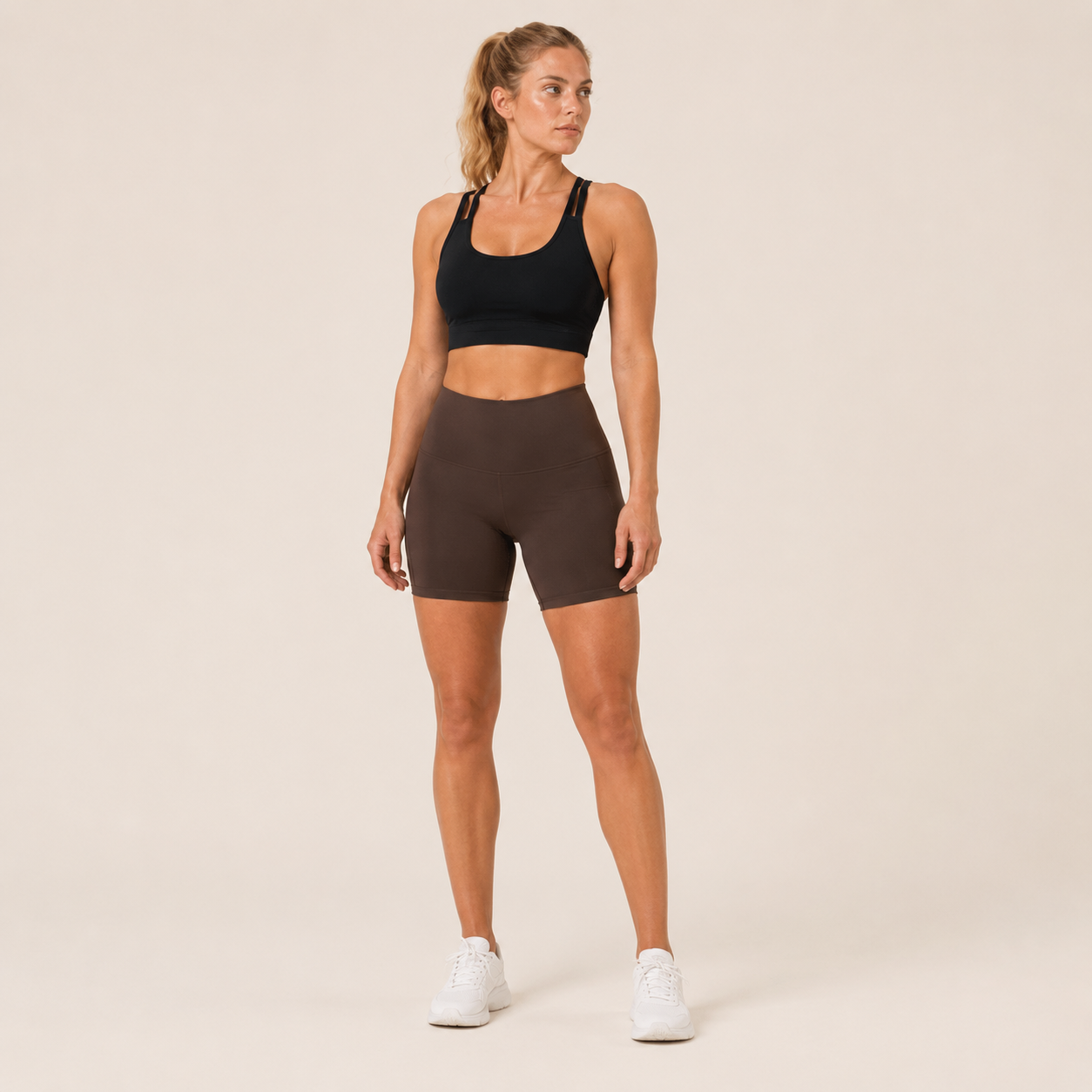 Full-body studio view of the black Fitfigura Studio Bra – Soft Flow, styled with fitted shorts and white sneakers.