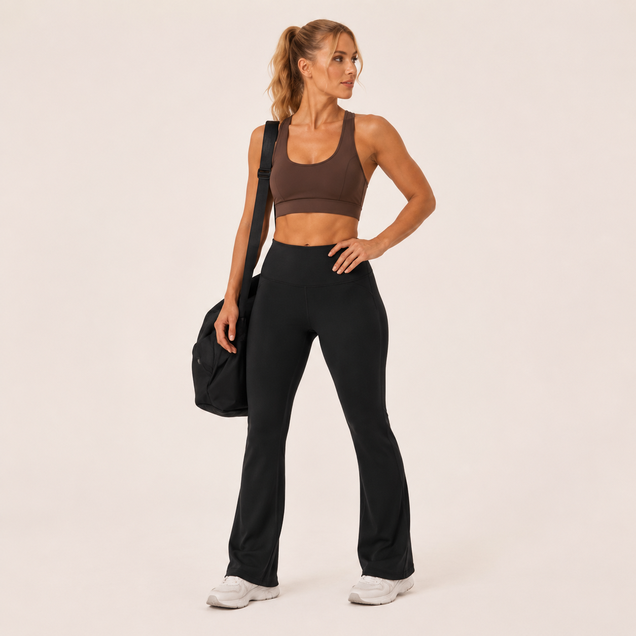 Model wearing the black Fitfigura Studio High Waist Flare Pant – Fluid Motion Form with a matching top and carrying a black bag.